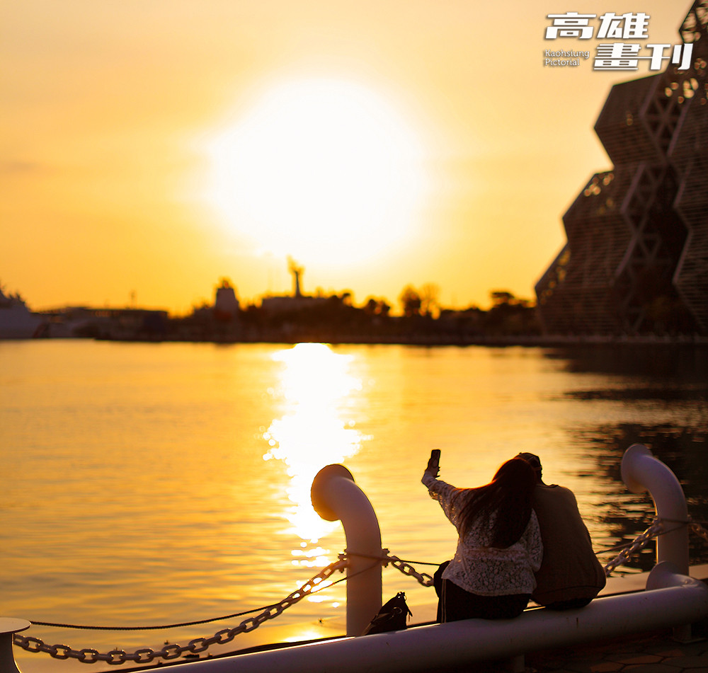 夕陽映照港灣水面，人們在河岸邊留影停留，為高雄的日常時刻添上一抹溫柔光景。