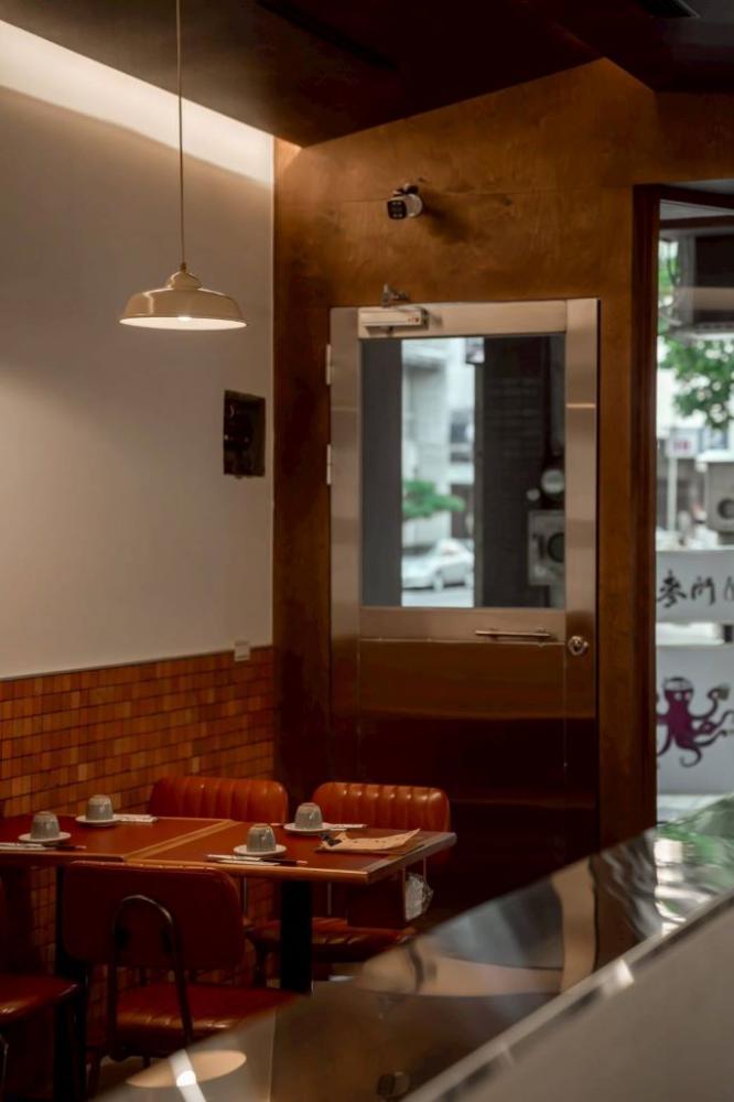 步入室內，暖黃燈光灑落在帶有紅色元素的皮質座椅，營造出既復古又自在的聚餐氛圍