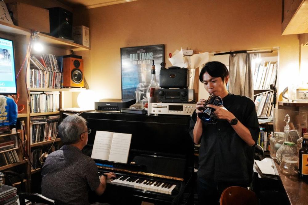 老闆與熟客一人坐上鋼琴、一人拿起小號，即興演奏起 Bill Evans 的經典爵士曲目