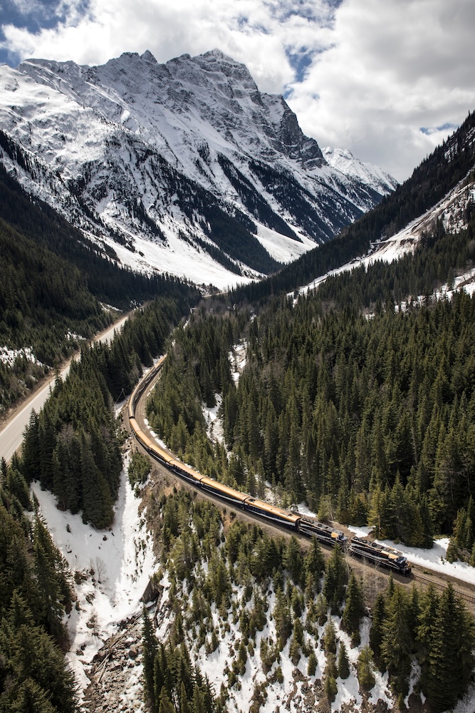 列車穿行於高山與河谷之間，窗外可能遇見加拿大洛磯山脈最高峰羅布森山（Mount Robson）、湍急河流與大片森林。